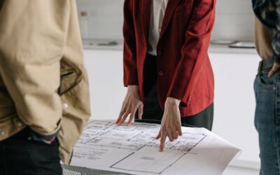 Un professionnel de l’immobilier discute des plans architecturaux avec les clients dans un bureau.