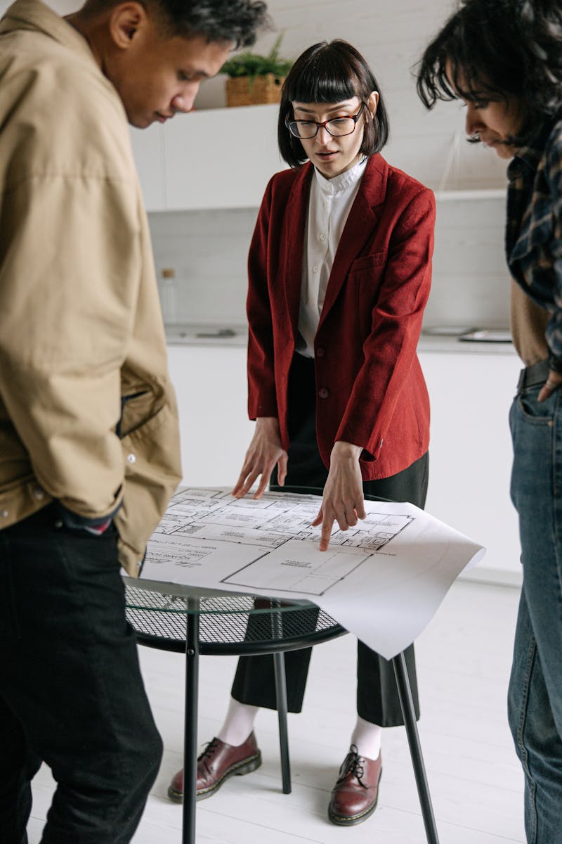 Un professionnel de l’immobilier discute des plans architecturaux avec les clients dans un bureau.